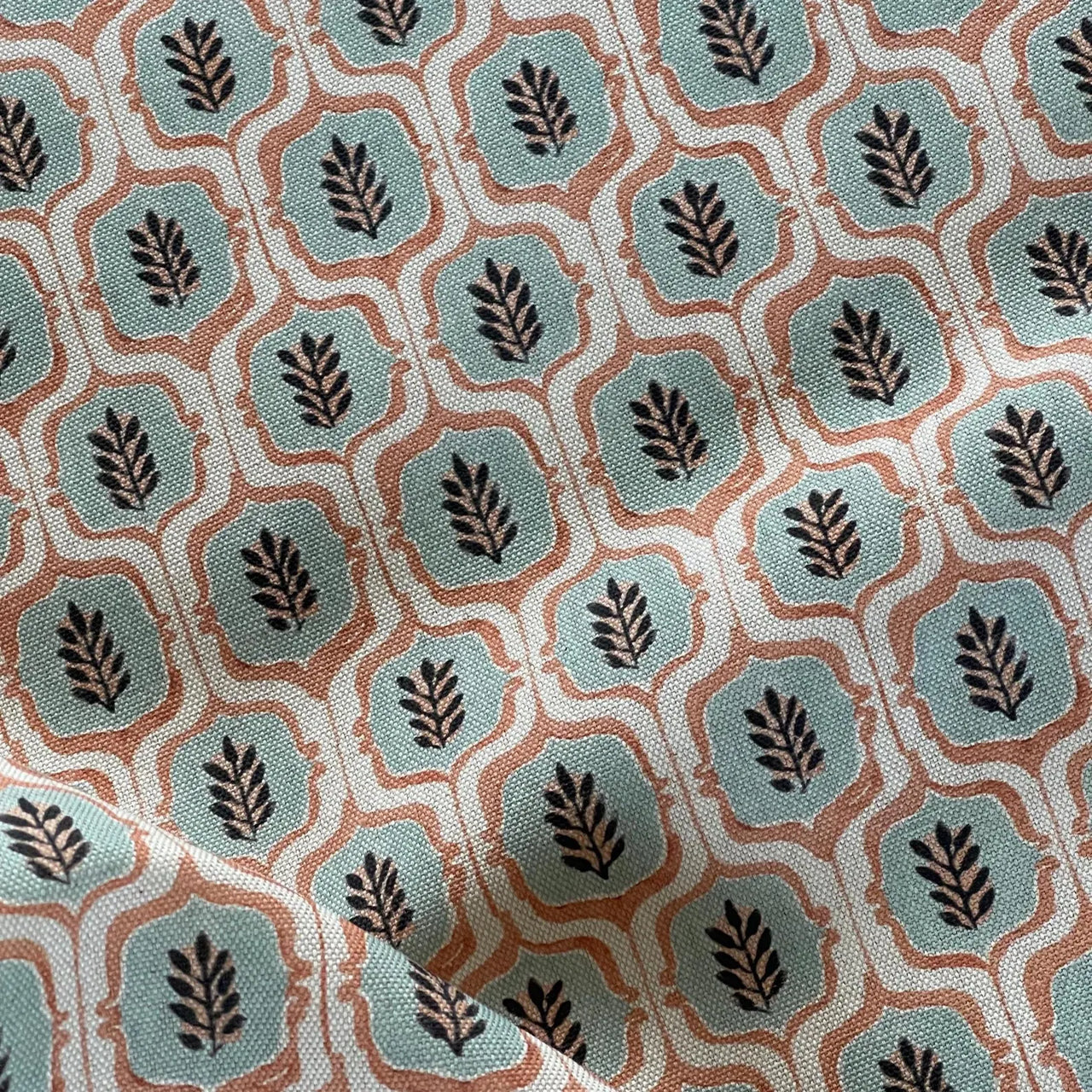 Woven trellis fabric displayed on roll in teal tones.