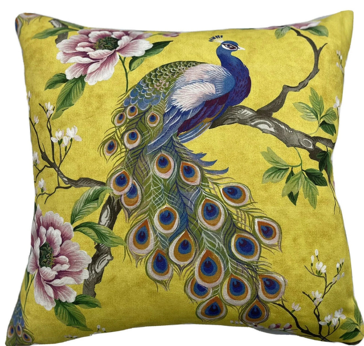 Peacock cushion cover with floral design on yellow background.

