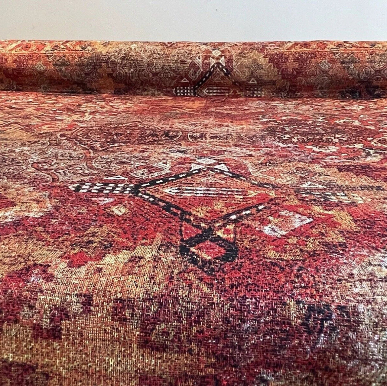 Roll of patterned red and brown fabric with a visible brand logo.
