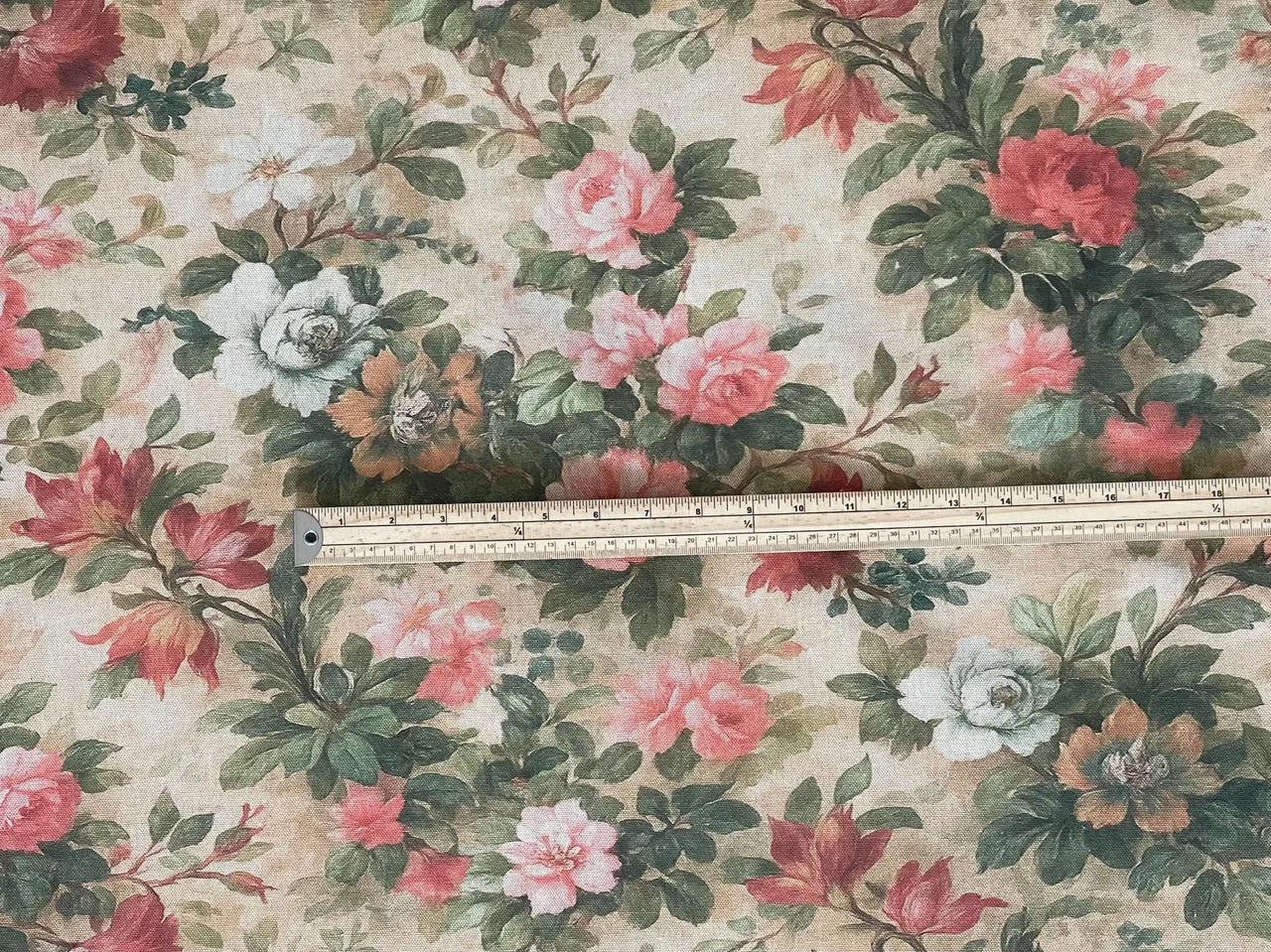 Close-up view of Vintage Rose Garden cotton floral fabric with measuring ruler, showing detailed rose and leaf pattern in pink, coral, green, and beige tones, ideal for curtains and blinds.