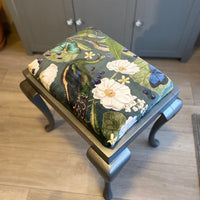 Thumbnail for Decorative ottoman with floral and bird pattern on a wooden floor.
