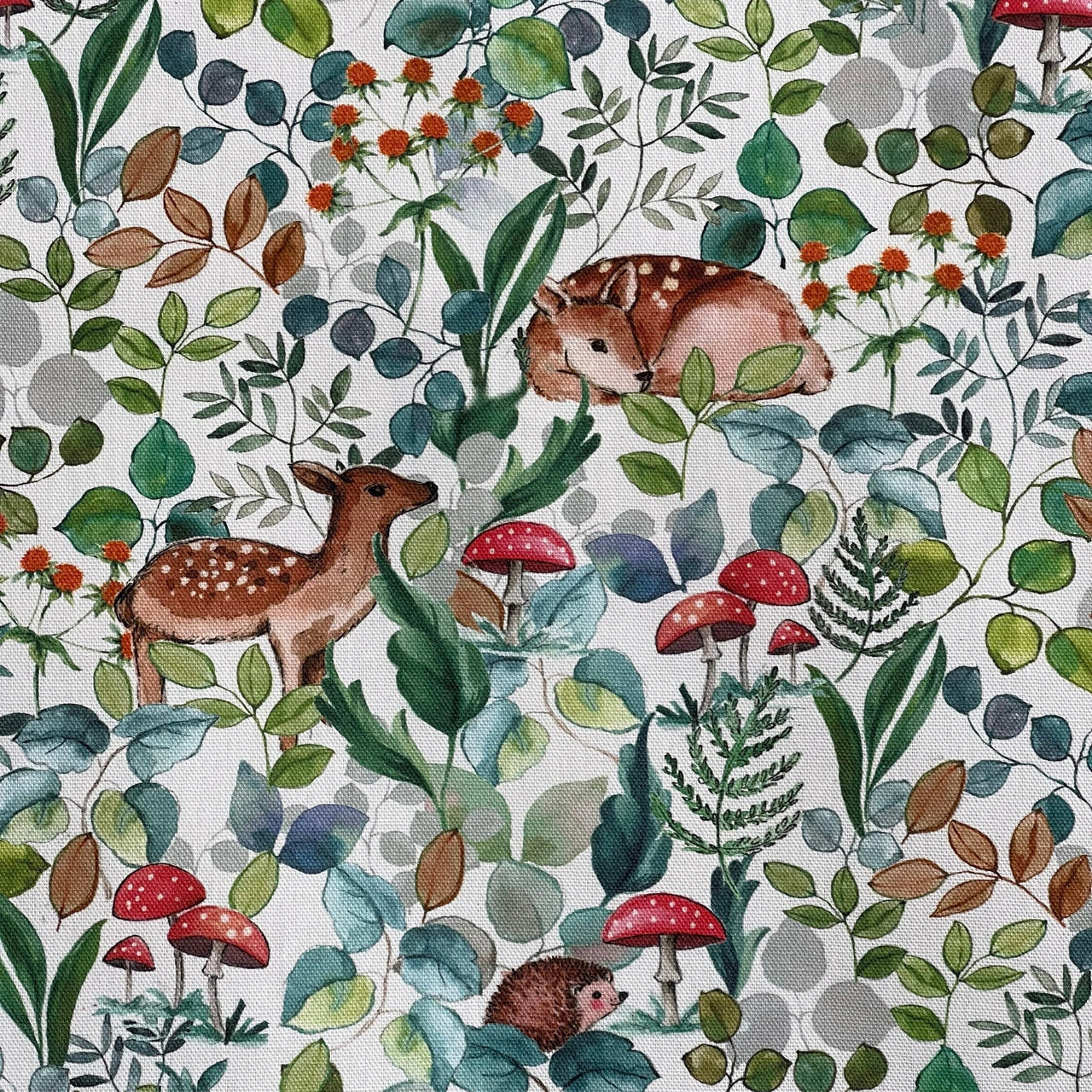 Close-up of printed cotton fabric featuring Bambi deer, red mushrooms, and forest plants on a white base.


