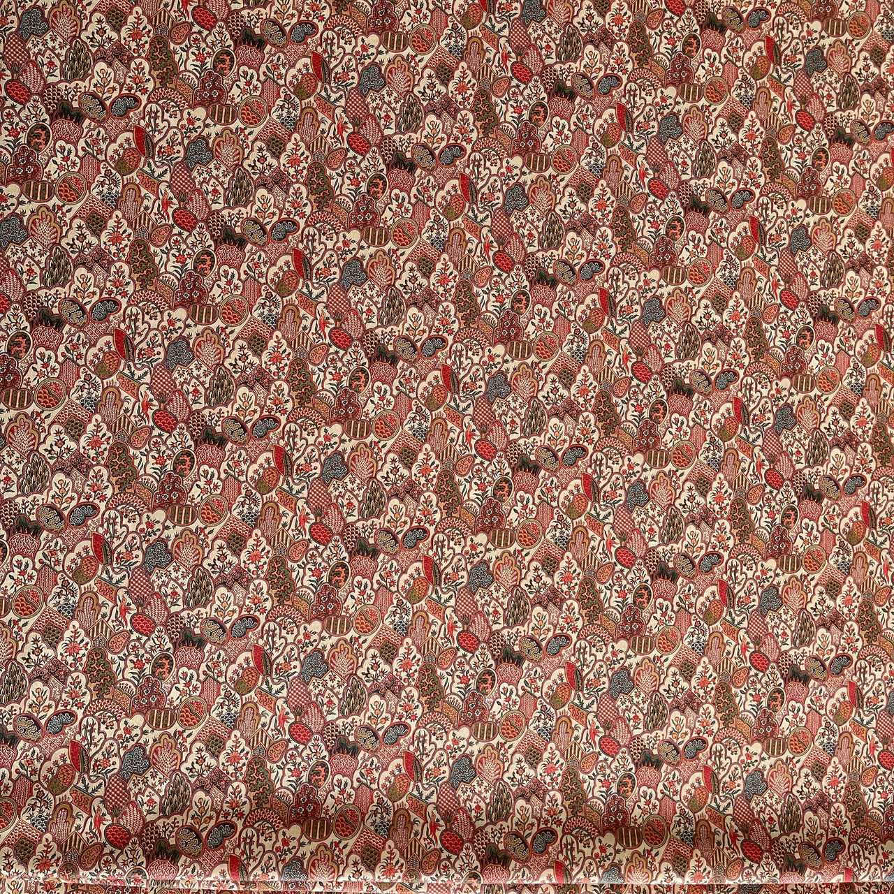 Textile pattern with small, intricate design in red, brown, and beige.