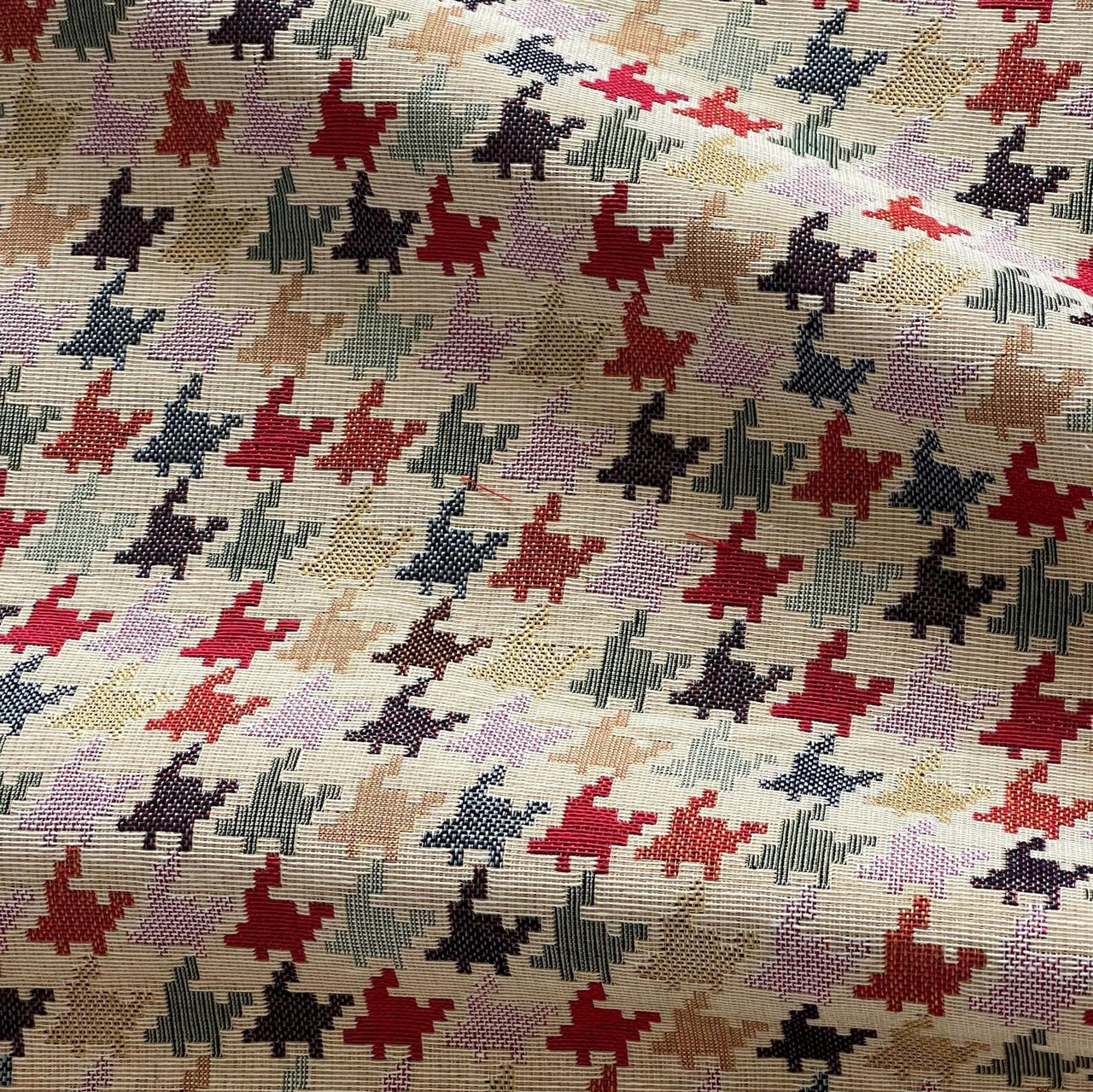 Patterned fabric with red, black, and beige shapes on a textured background