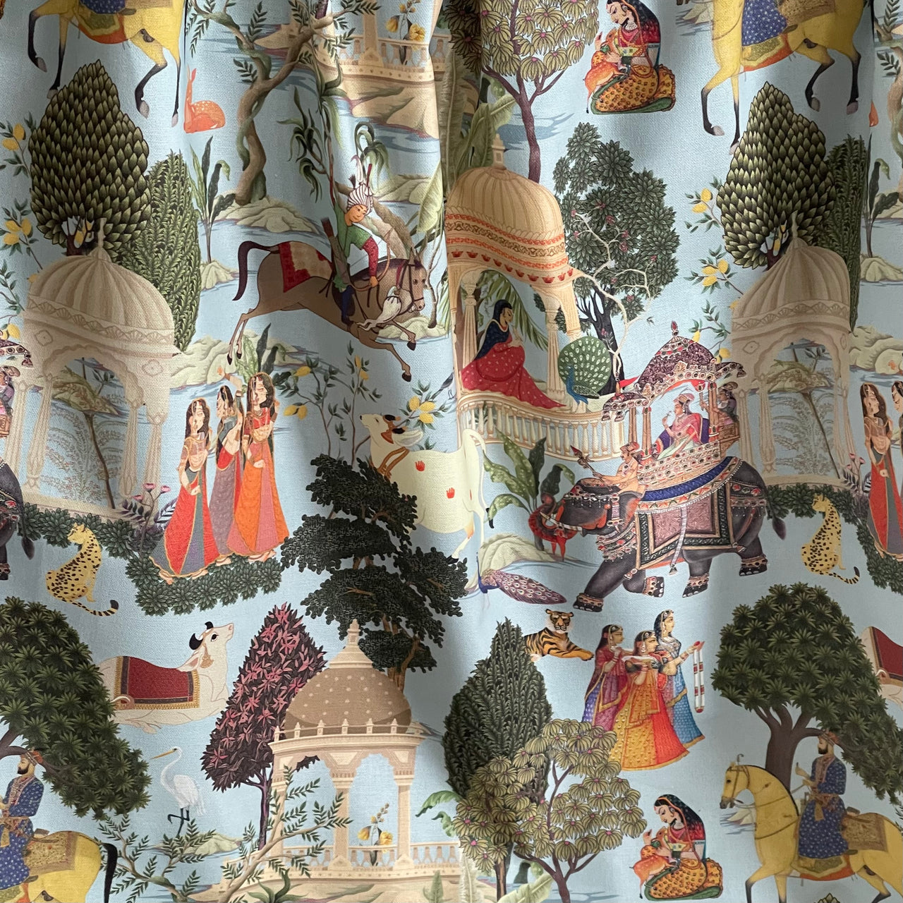 Draped Regalia pattern cotton fabric styled as a curtain, displaying vibrant Indian heritage scenes and soft folds.