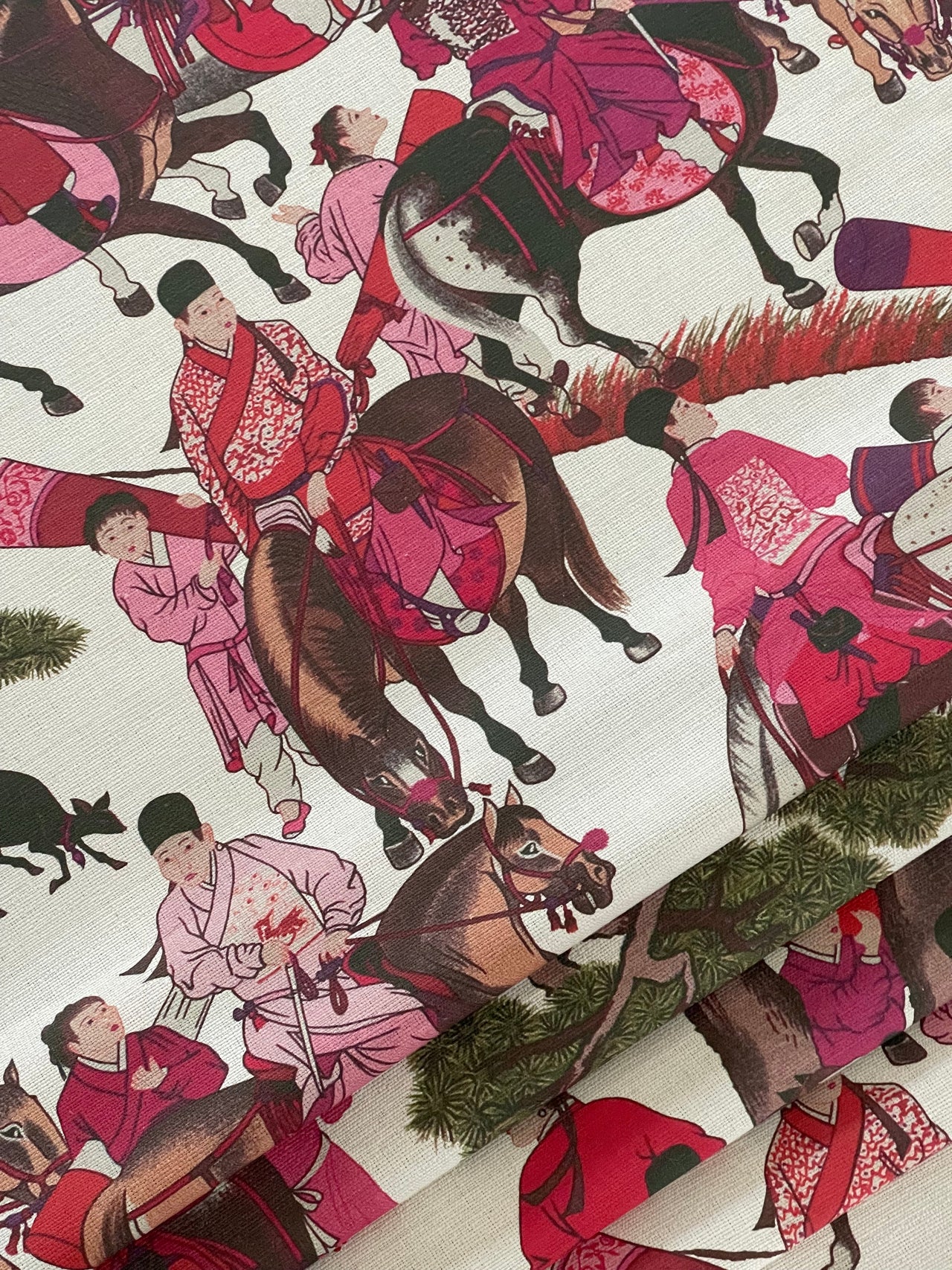 Close-up of Mongolian riders in red and pink on beige cotton textile