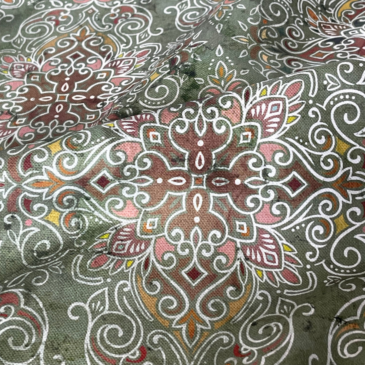 Close-up of patterned fabric with intricate designs on a green background