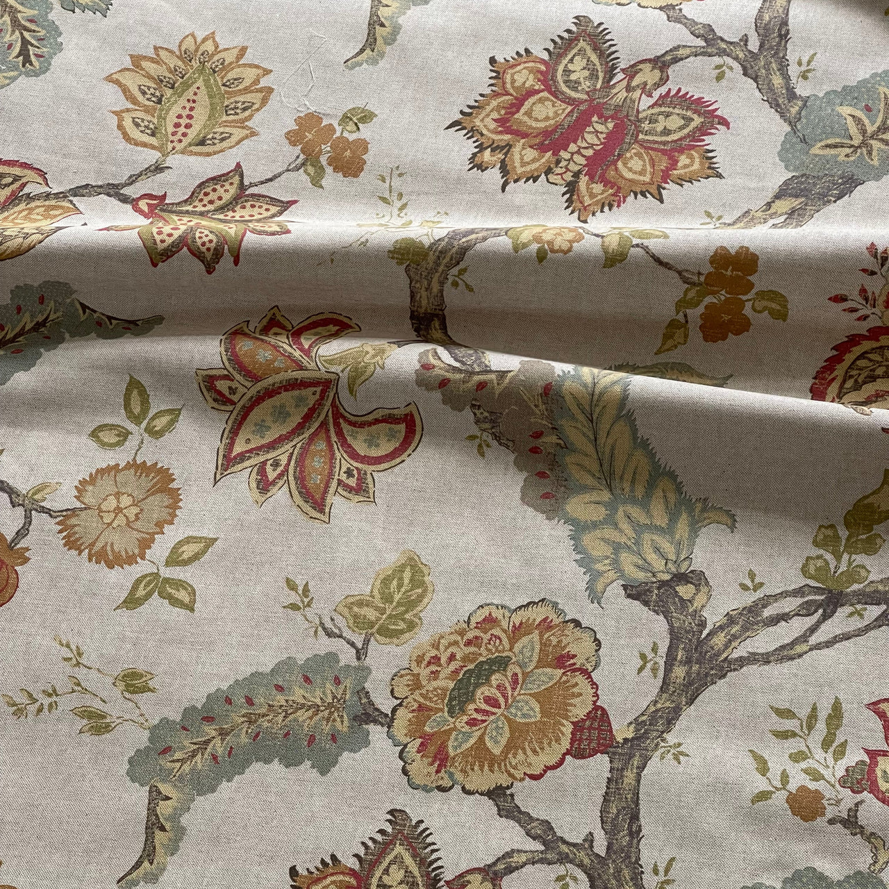 Floral patterned fabric with red, green, and brown colors on a neutral background