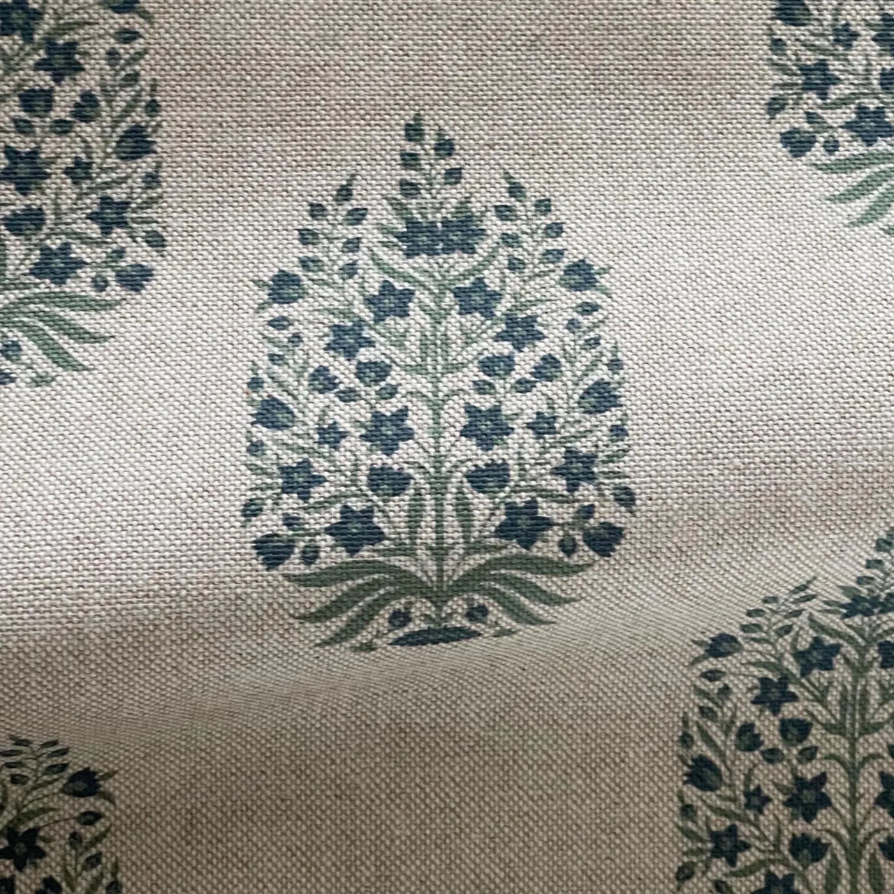 Soft blue botanical medallion fabric on natural linen look background close up