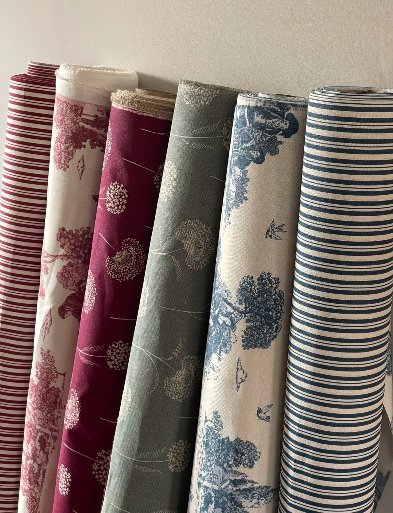 Rolls of patterned fabric in various colors and designs.