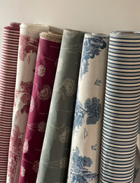 Thumbnail for Rolls of patterned fabric in various colors and designs.