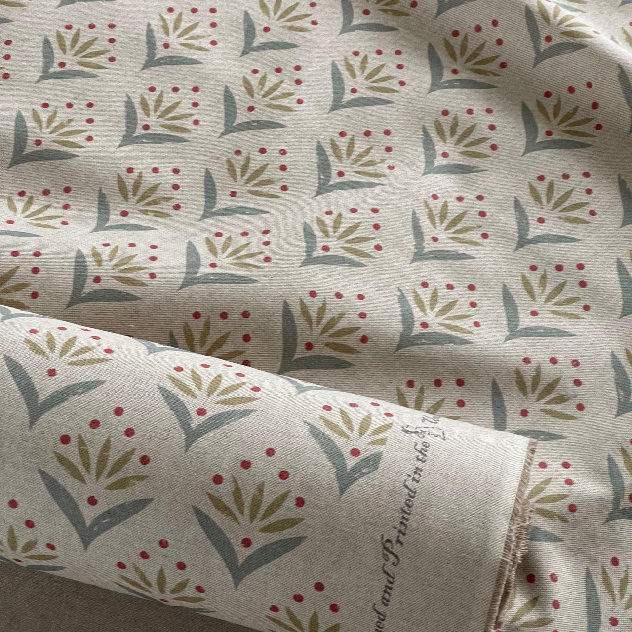 Botanical duckegg cotton blend upholstery fabric close up showing meadow motif pattern.