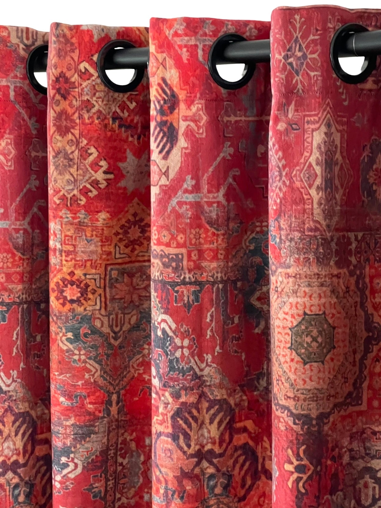 Red patterned curtains with grommets on a black rod.