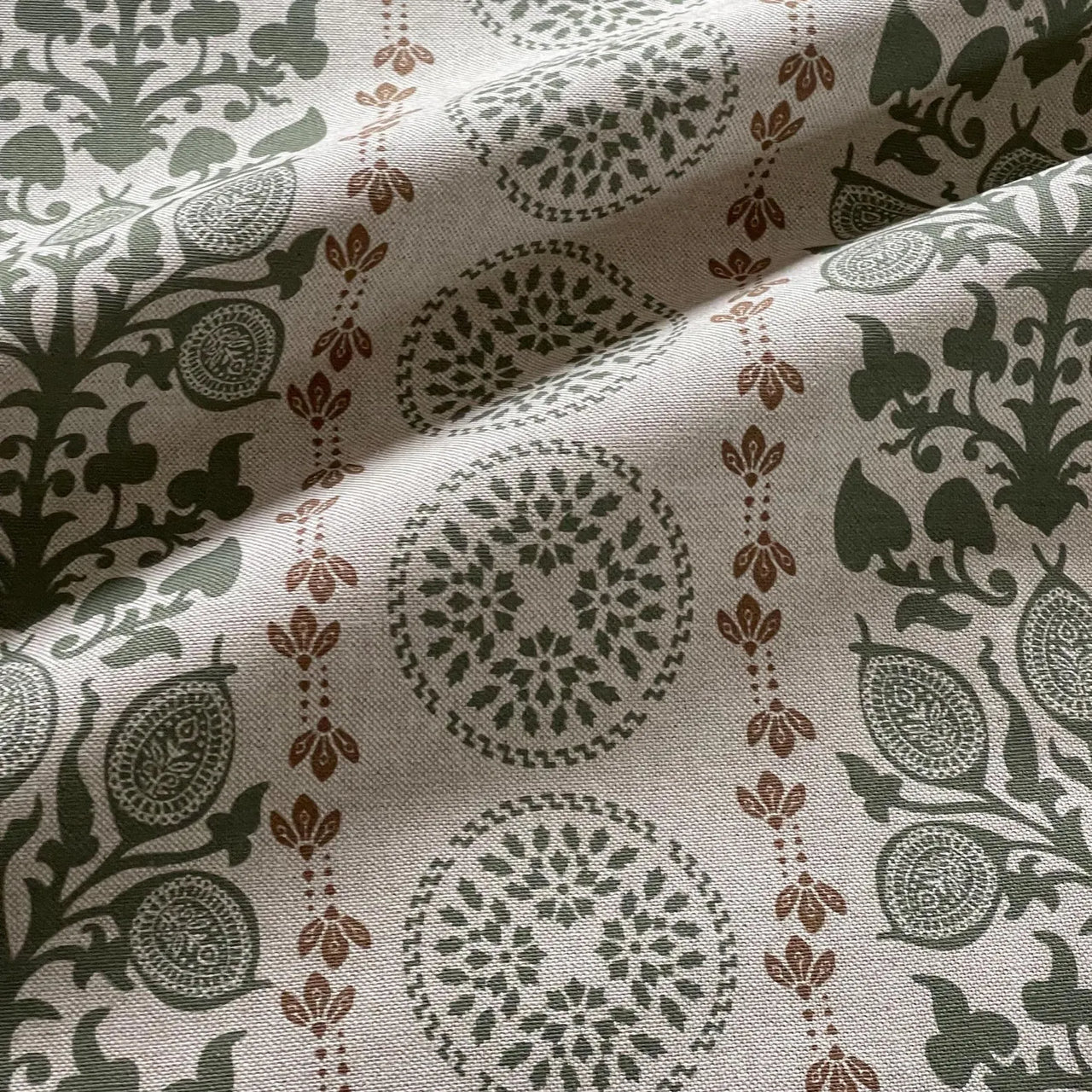 Soft sage green fabric with heritage medallion and floral detailing close up