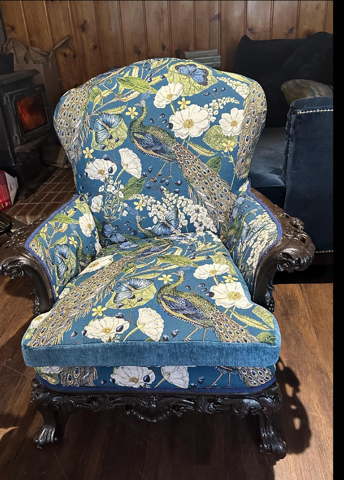 Decorative armchair with floral and peacock pattern in a room setting.
