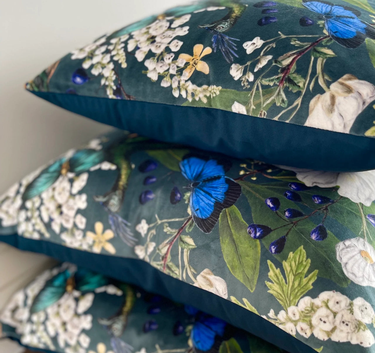 Floral and butterfly patterned cushions on a plain background