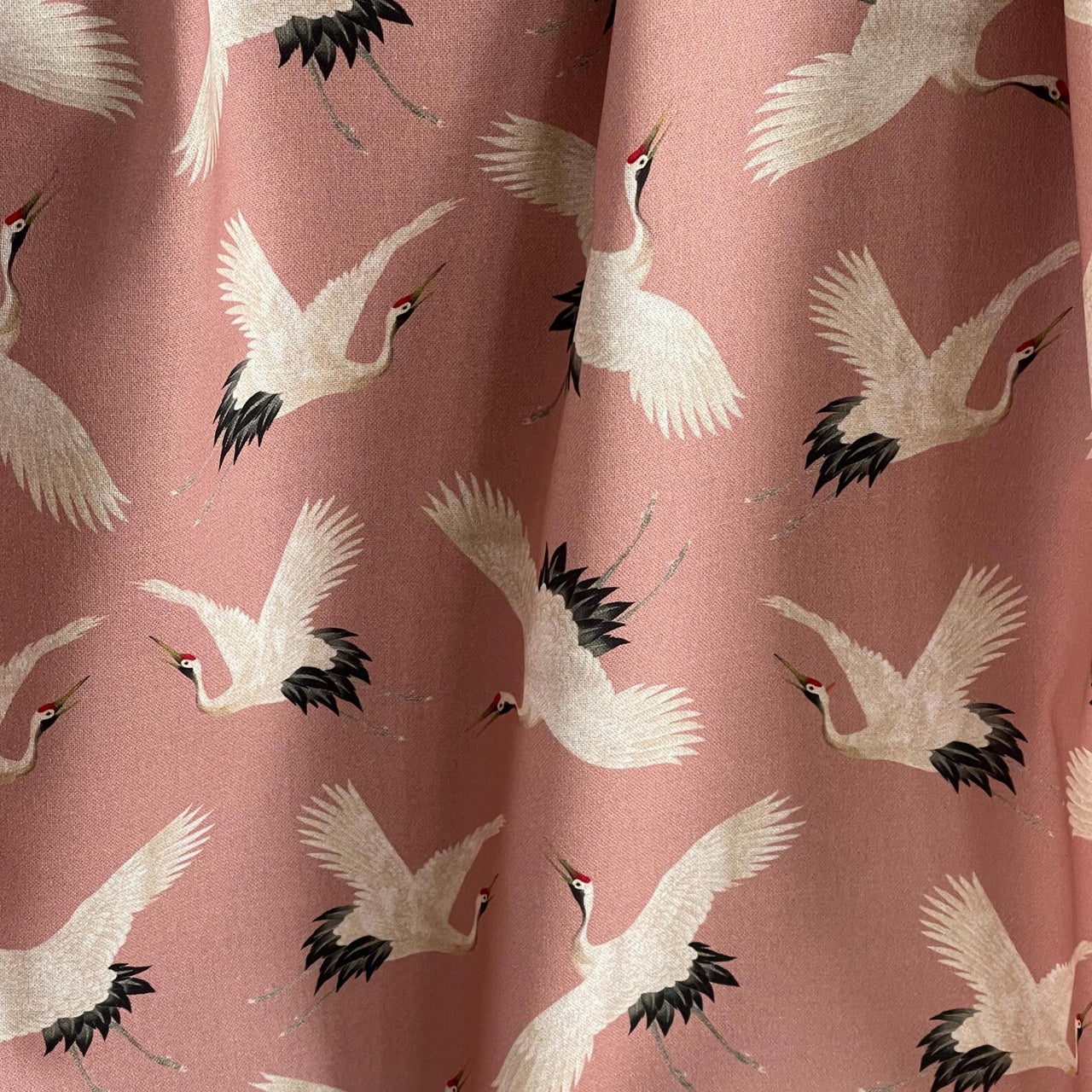 Cotton drapery fabric with soft blush tone and crane illustrations.