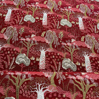 Thumbnail for Red fabric with a nature-themed pattern featuring trees and animals on a wooden surface.