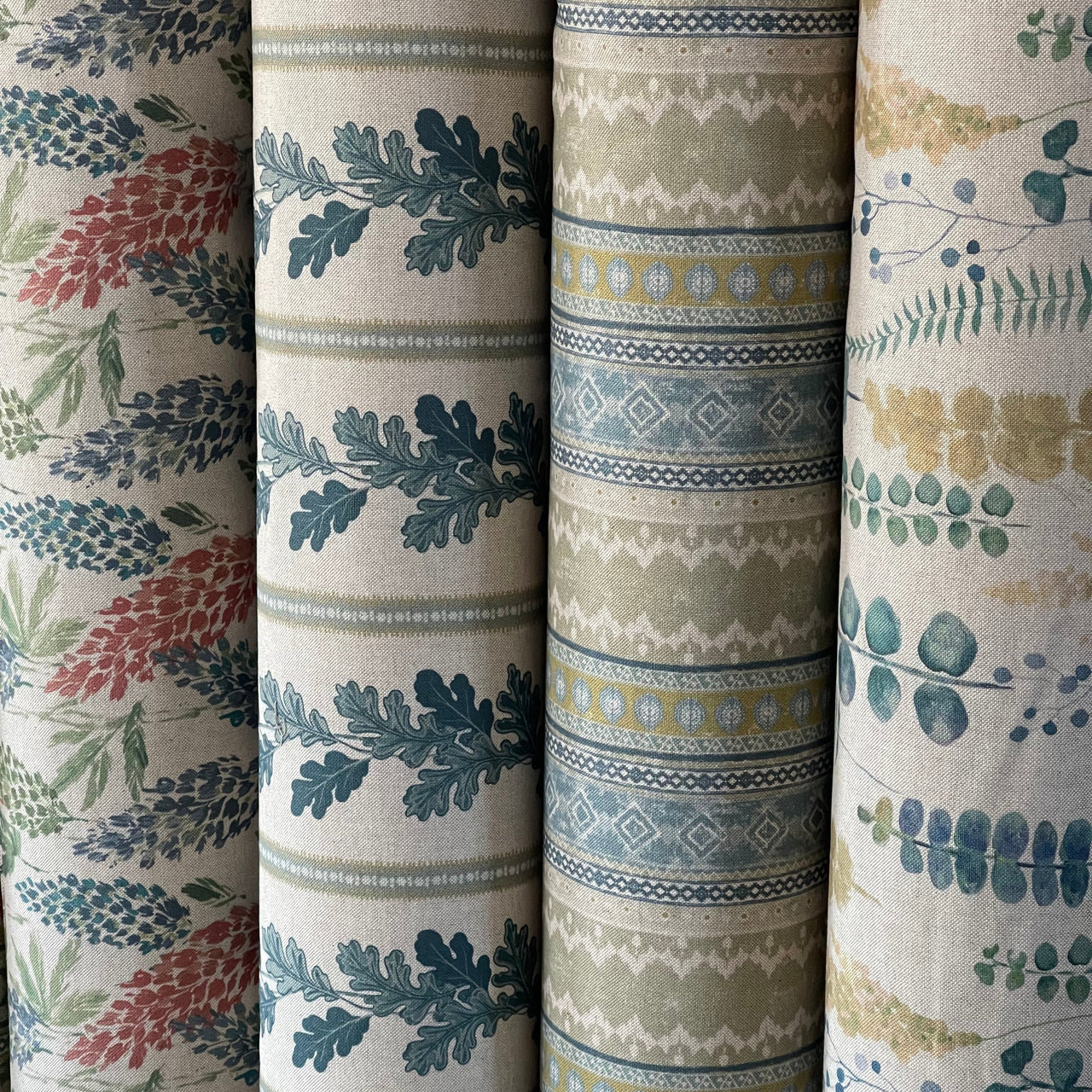Four rolls of fabric with different patterns and colors.