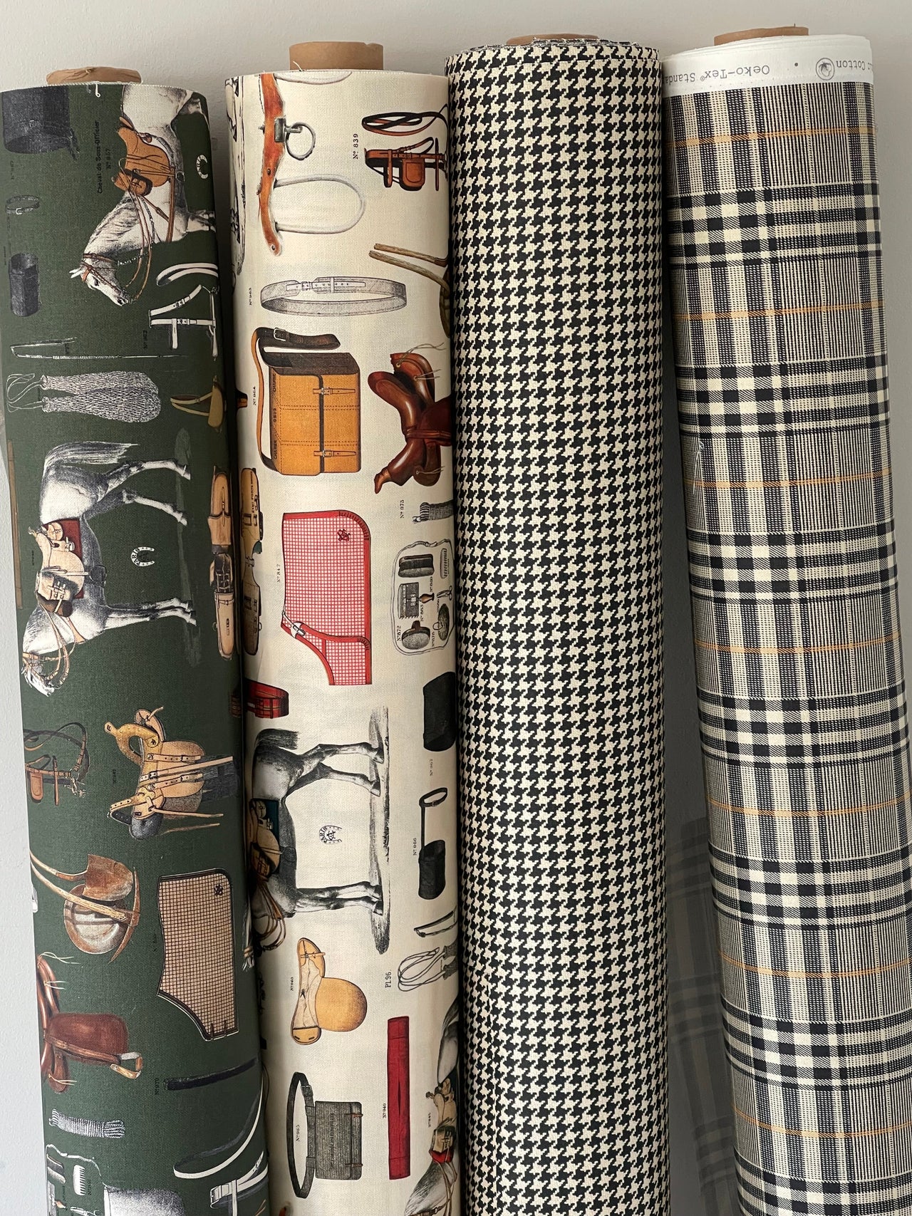 Four rolls of fabric with different patterns stacked on a light gray background