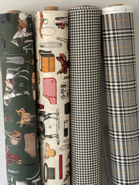 Thumbnail for Four rolls of fabric with different patterns stacked on a light gray background