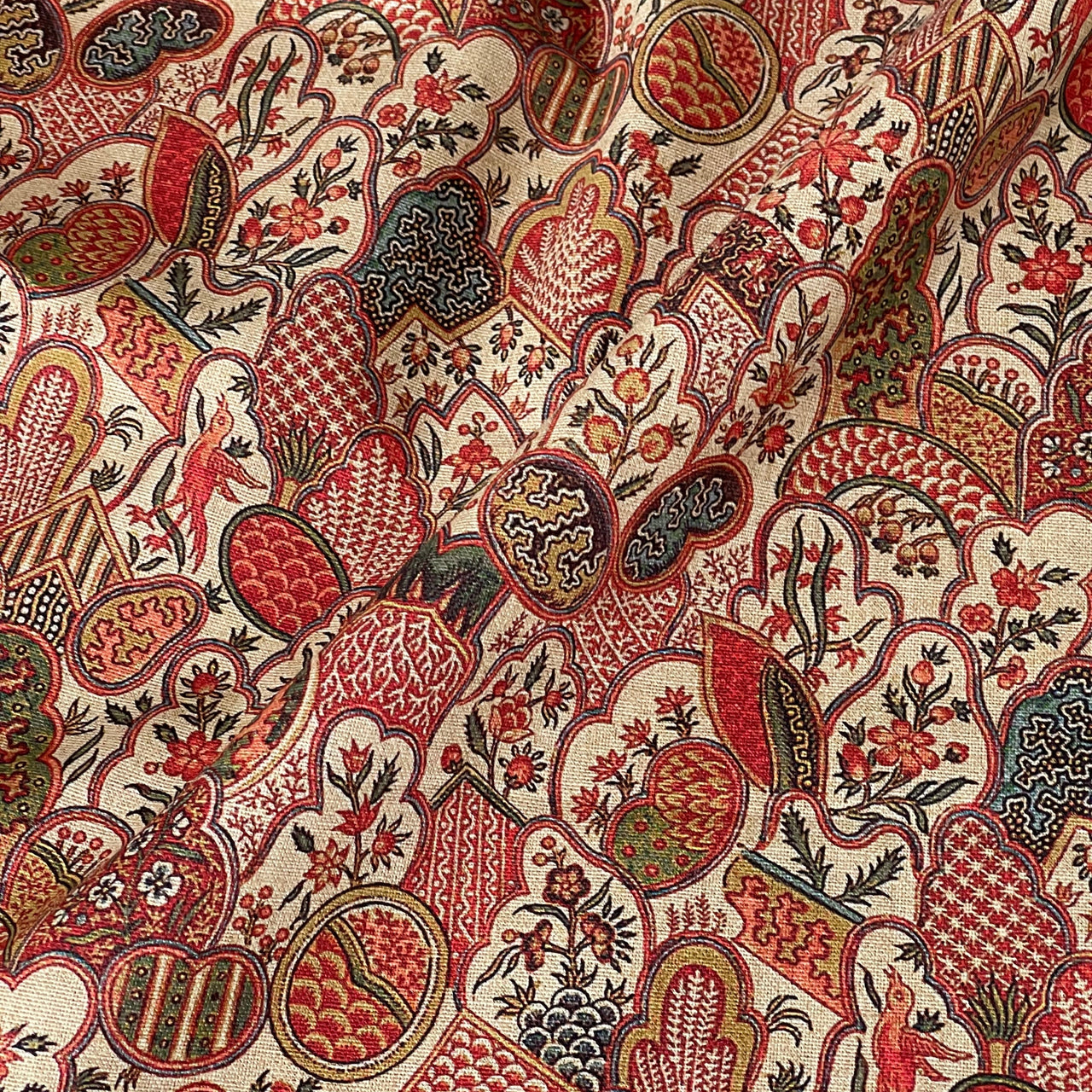 Close-up of intricate paisley patterned fabric with red, brown, and beige colors.