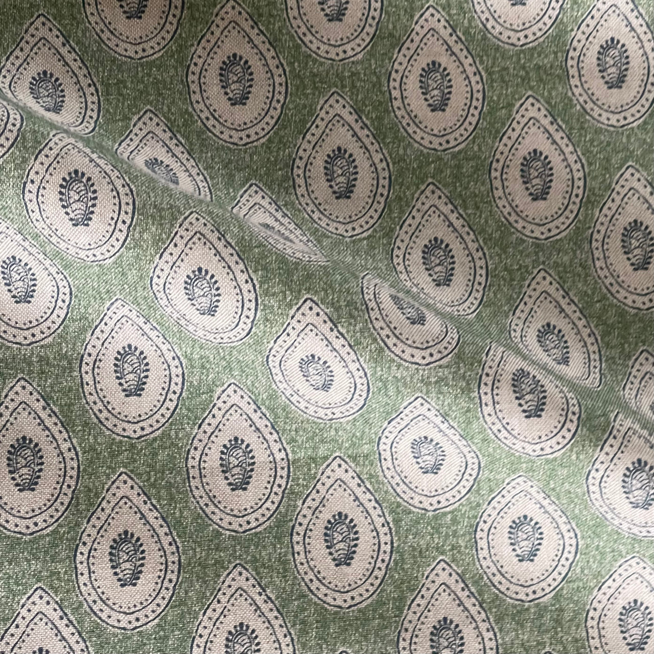 Green teardrop paisley fabric with Indian buta motif on linen look background