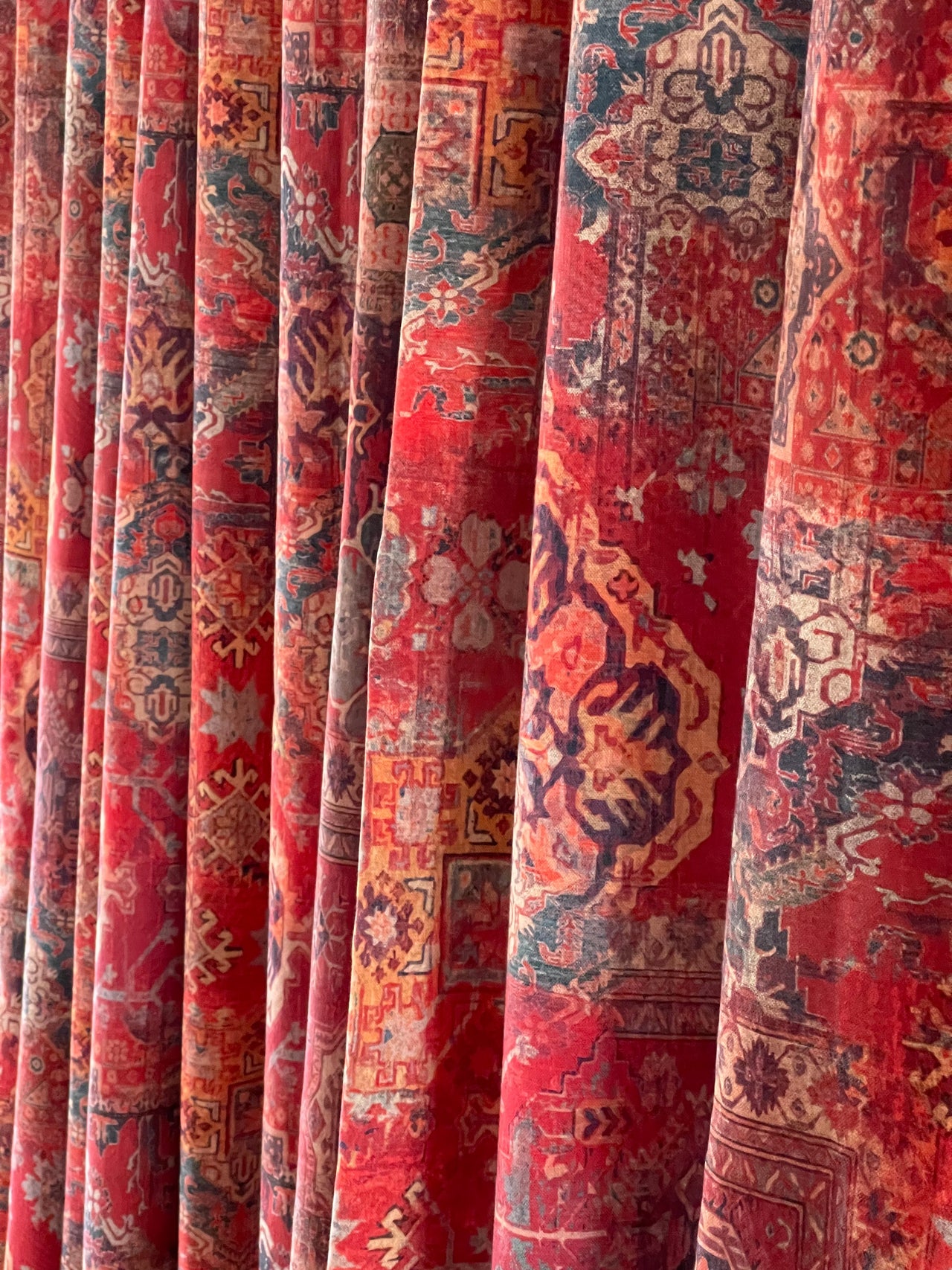 Cotton fabric with oriental rug pattern in red and orange hues.