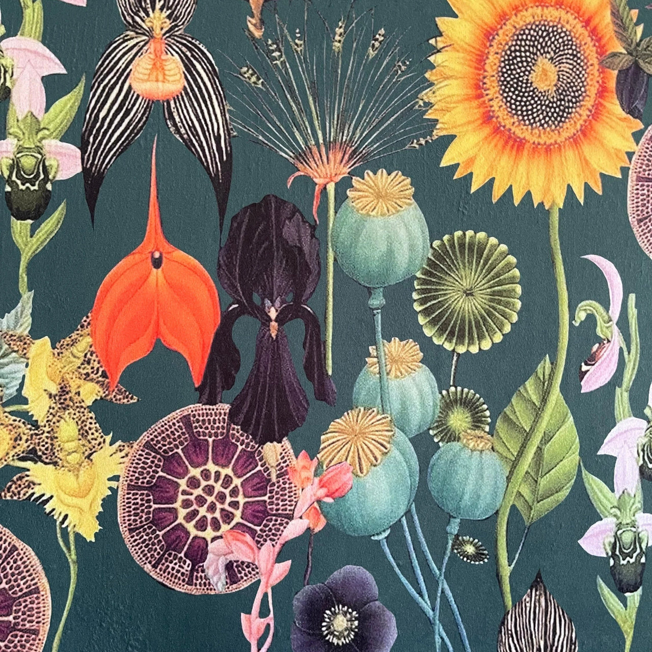 Close-up of printed velvet fabric showing vivid botanical elements including orchids, poppy pods, lotus seed heads, and sunflowers on a rich green background.

