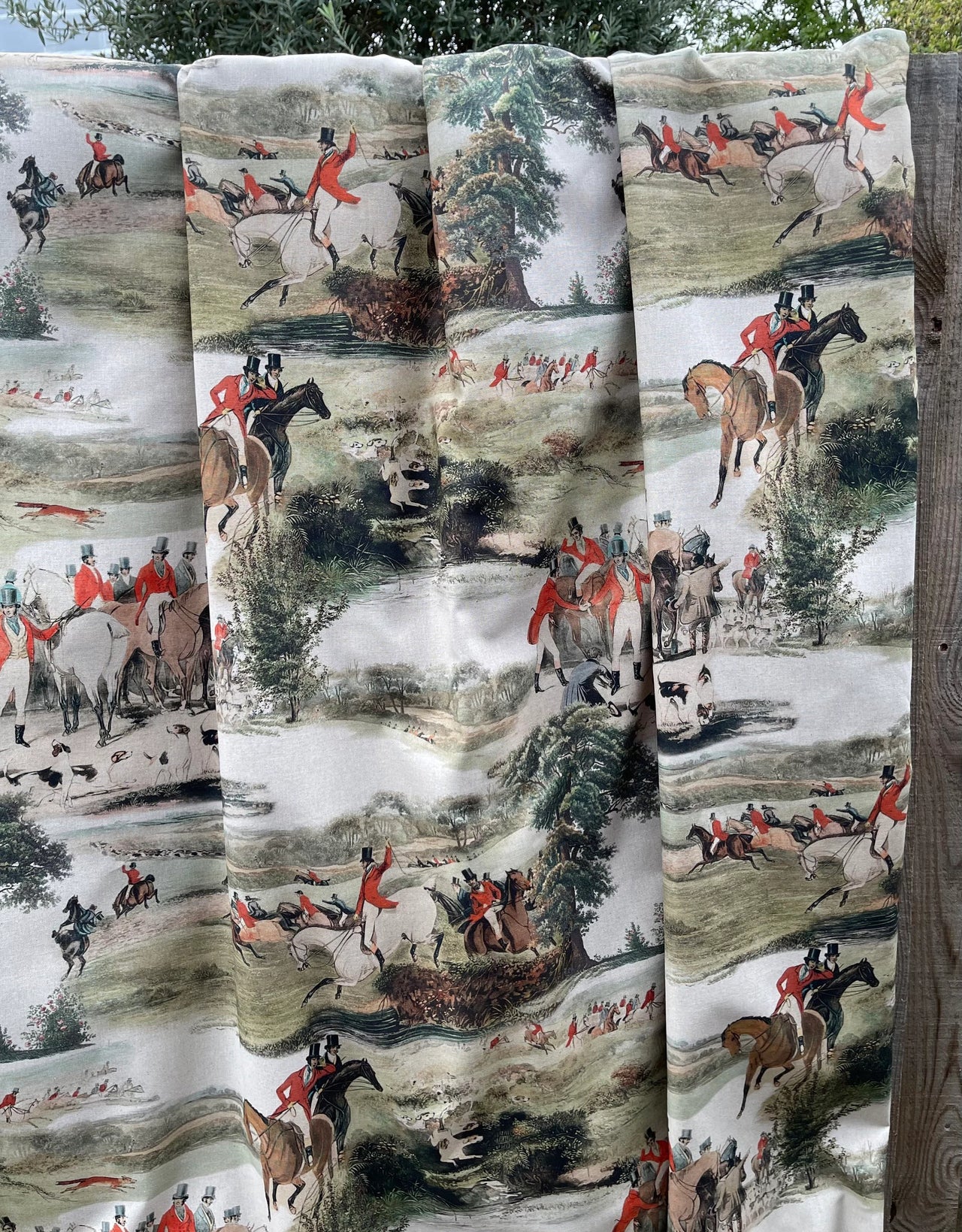 Fabric with hunting scene pattern displayed on a wooden surface