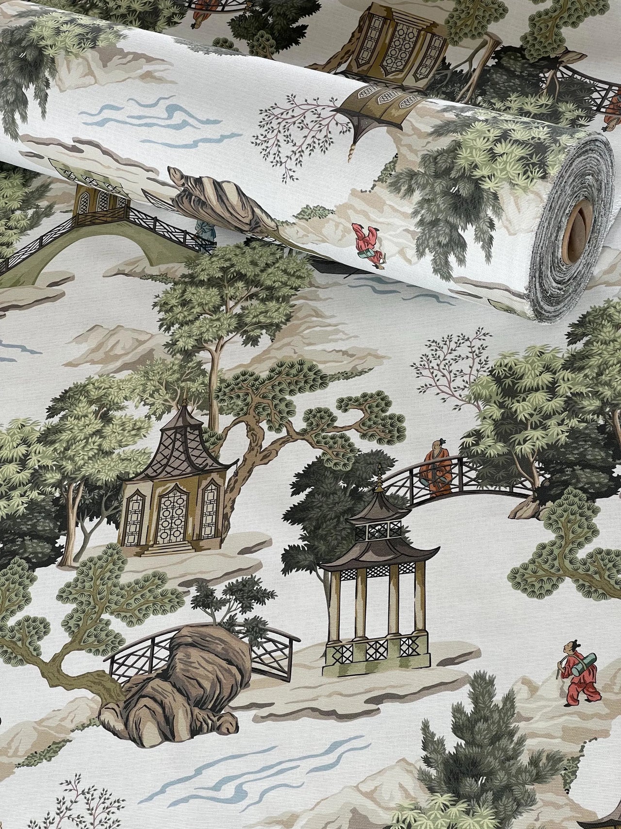 Roll of fabric with a scenic design featuring pagodas, trees, and people.