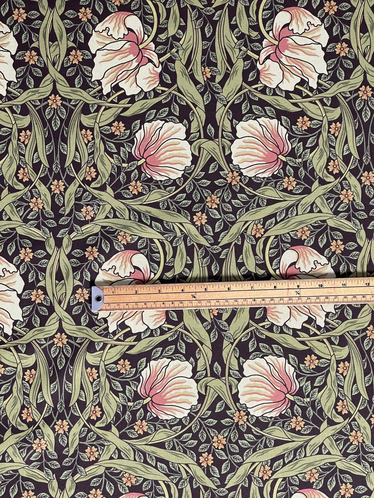 Floral fabric pattern with a ruler for scale on a dark background