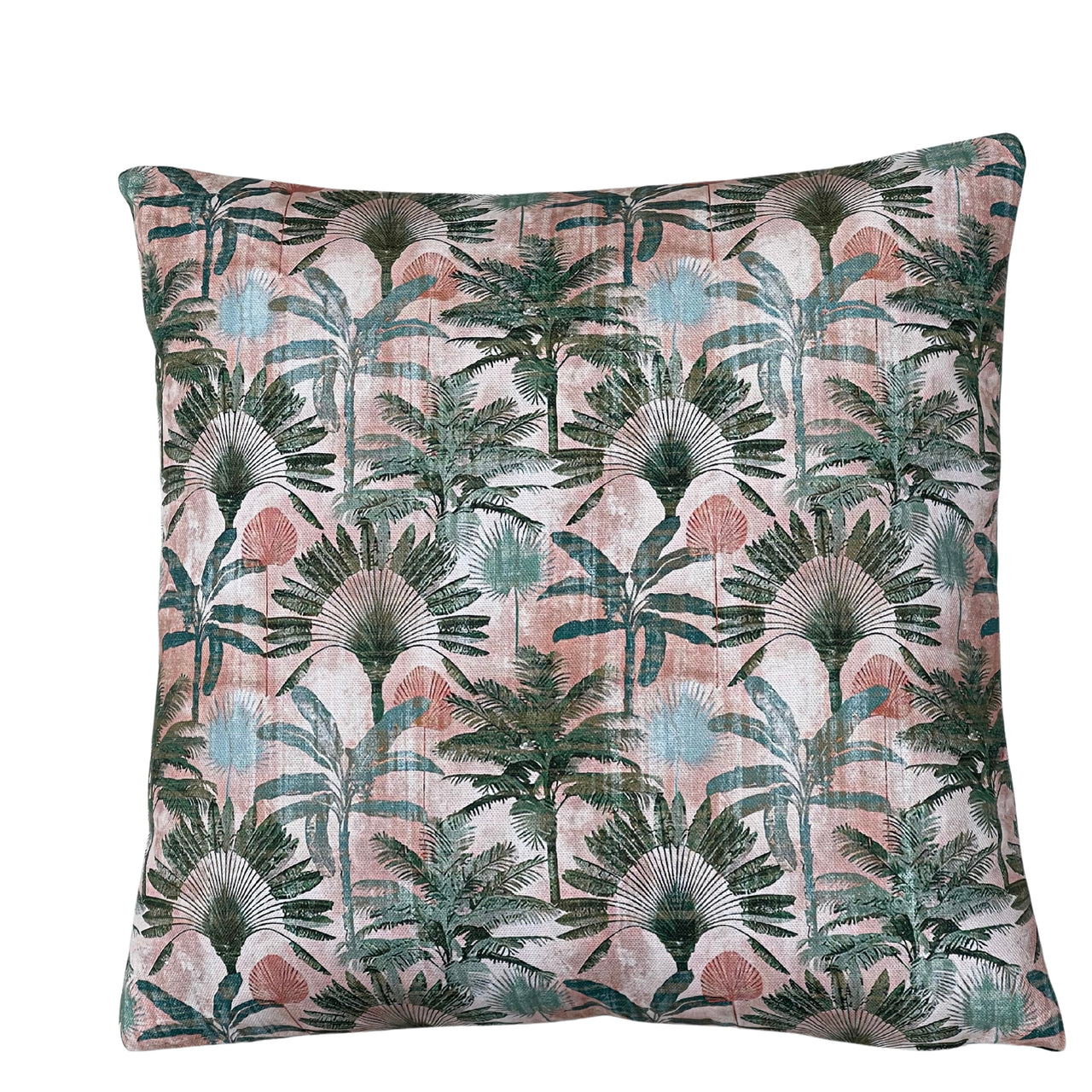 Close-up of blush pink tropical cushion fabric showing detailed fan palms, exotic green foliage and soft teal leaves in a botanical jungle pattern.