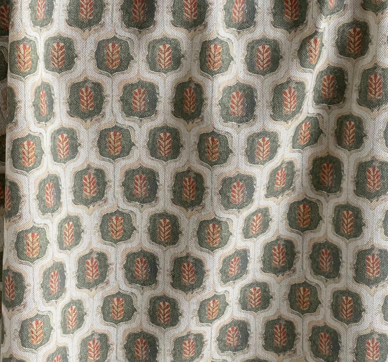 Detailed view of the textured botanical leaf fabric in olive green and warm rust