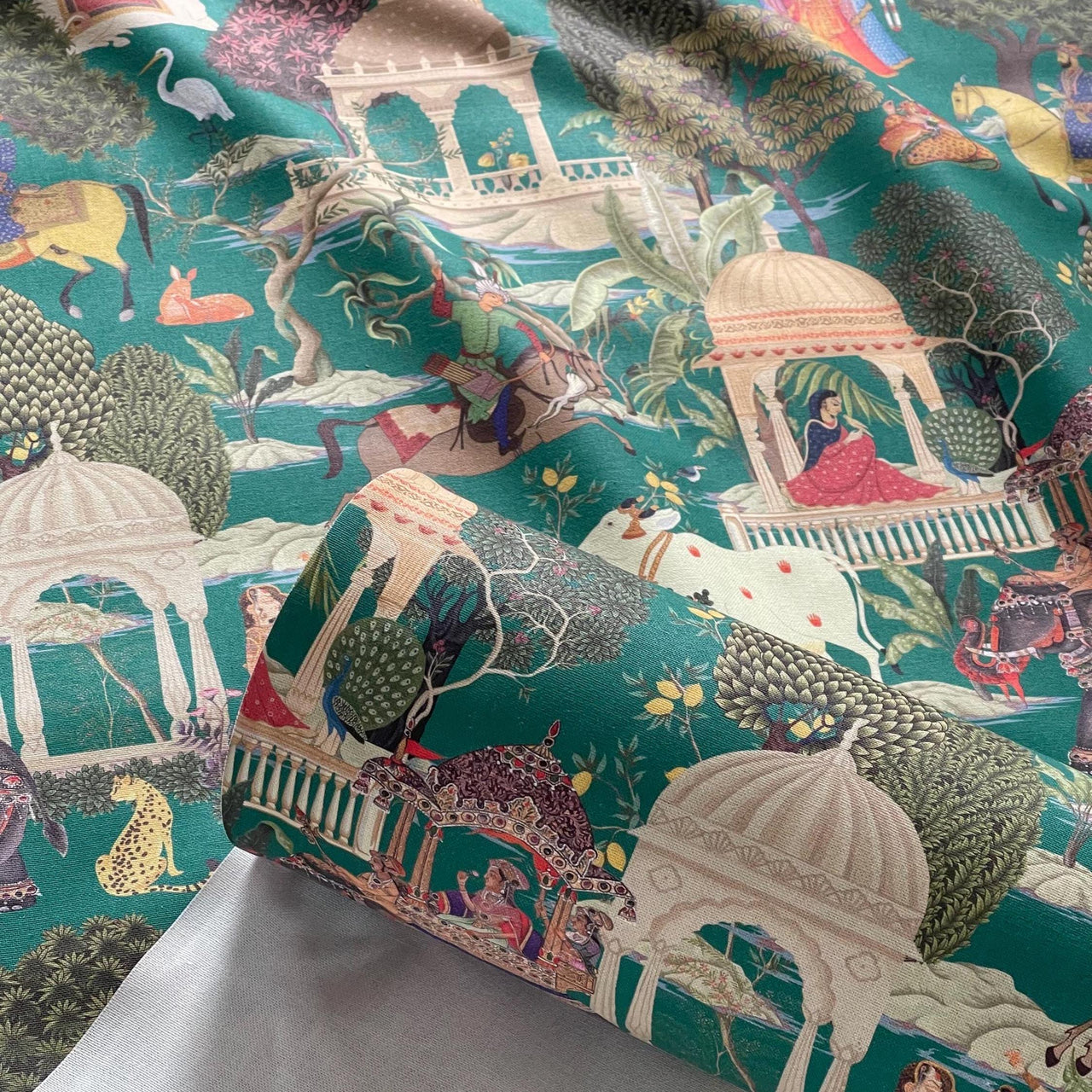 Regalia cotton fabric roll in emerald green featuring Mughal miniature design with royalty, domes, elephants, and intricate flora.