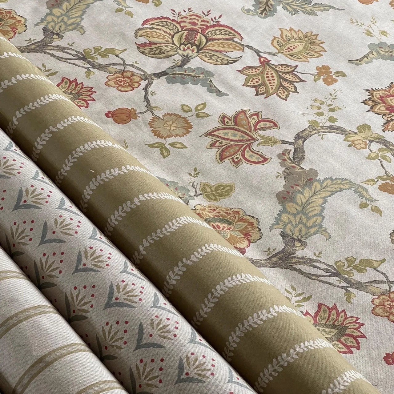Rolls of fabric with floral and stripe patterns on a neutral background