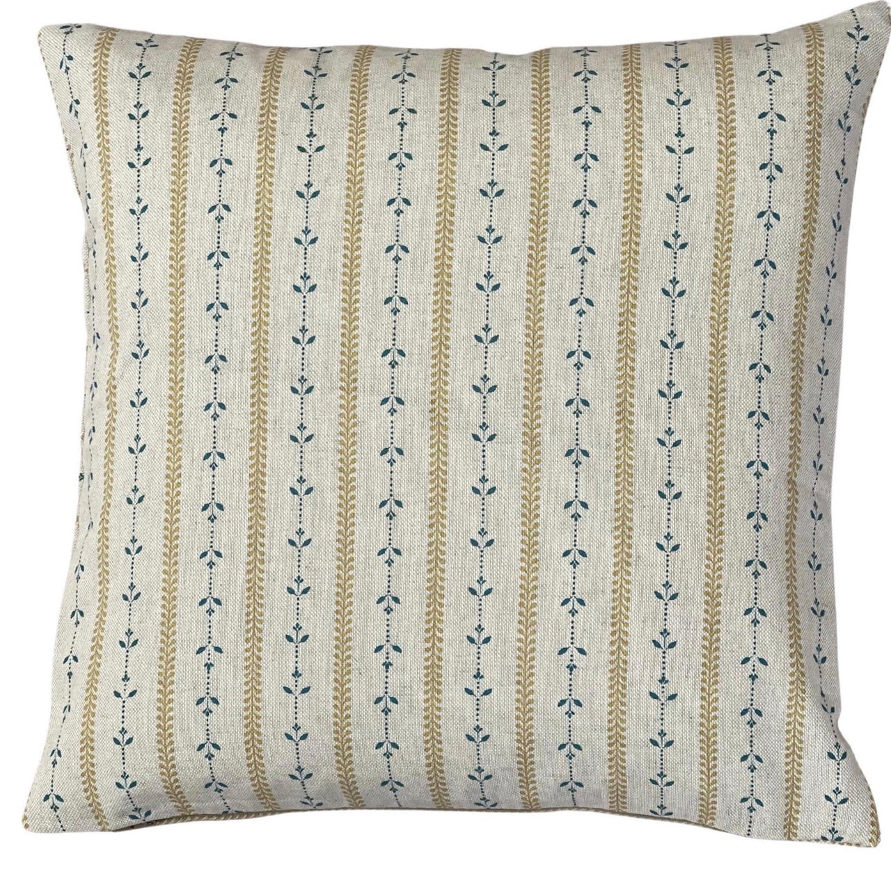 Close-up of golden wheat stripes and dusty blue leafy stems on a cushion cover