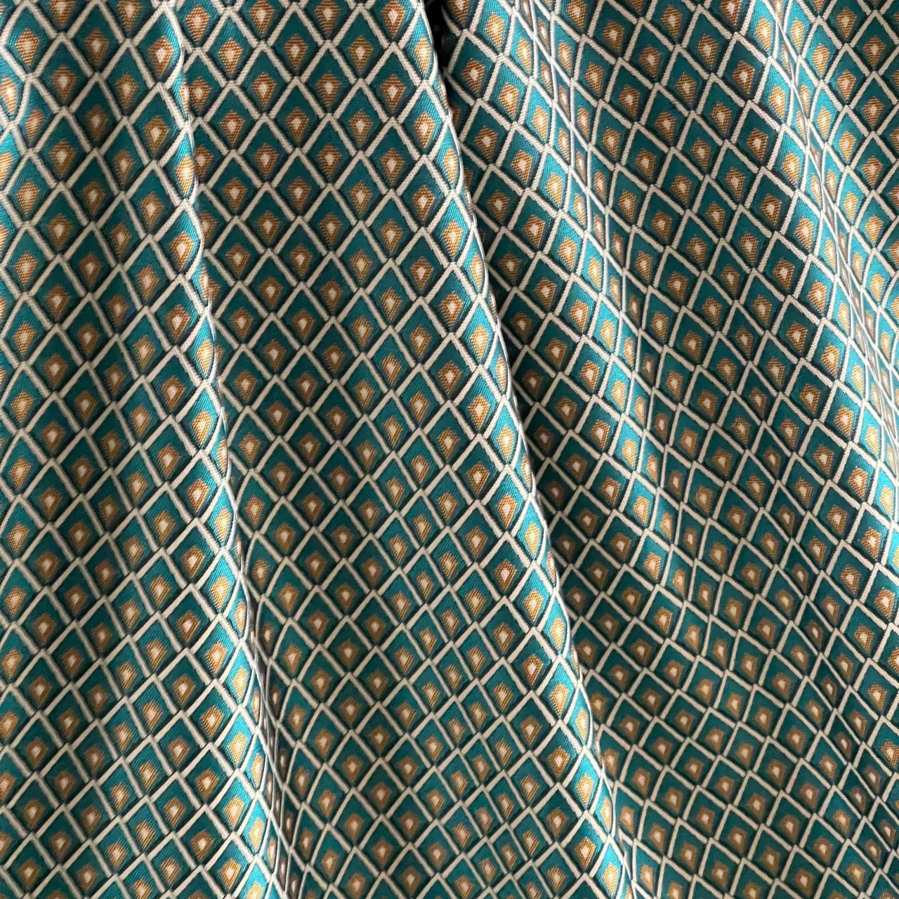 Teal blue and gold geometric lattice curtain fabric close-up view