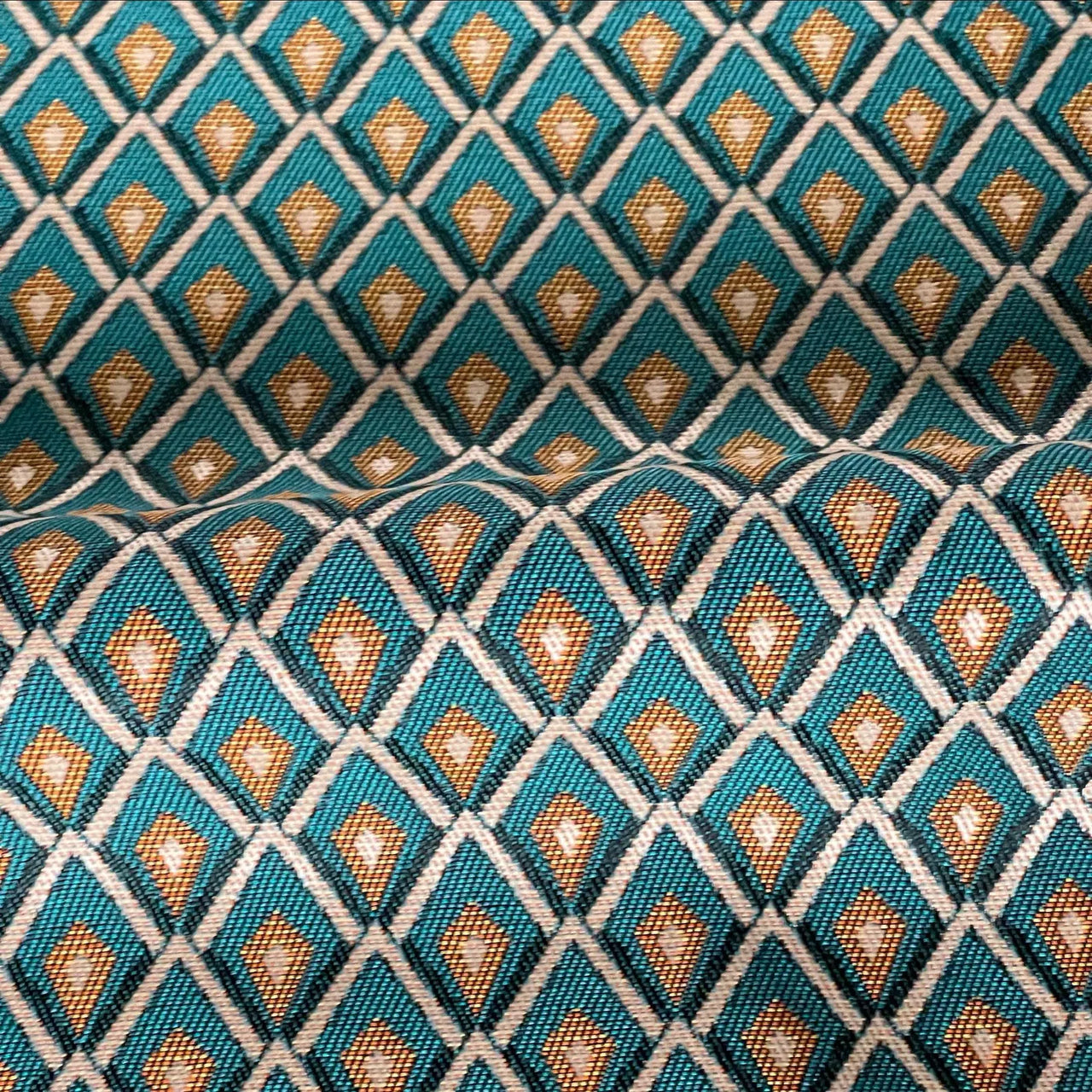 Small-scale lattice repeat on woven teal and gold drapery fabric