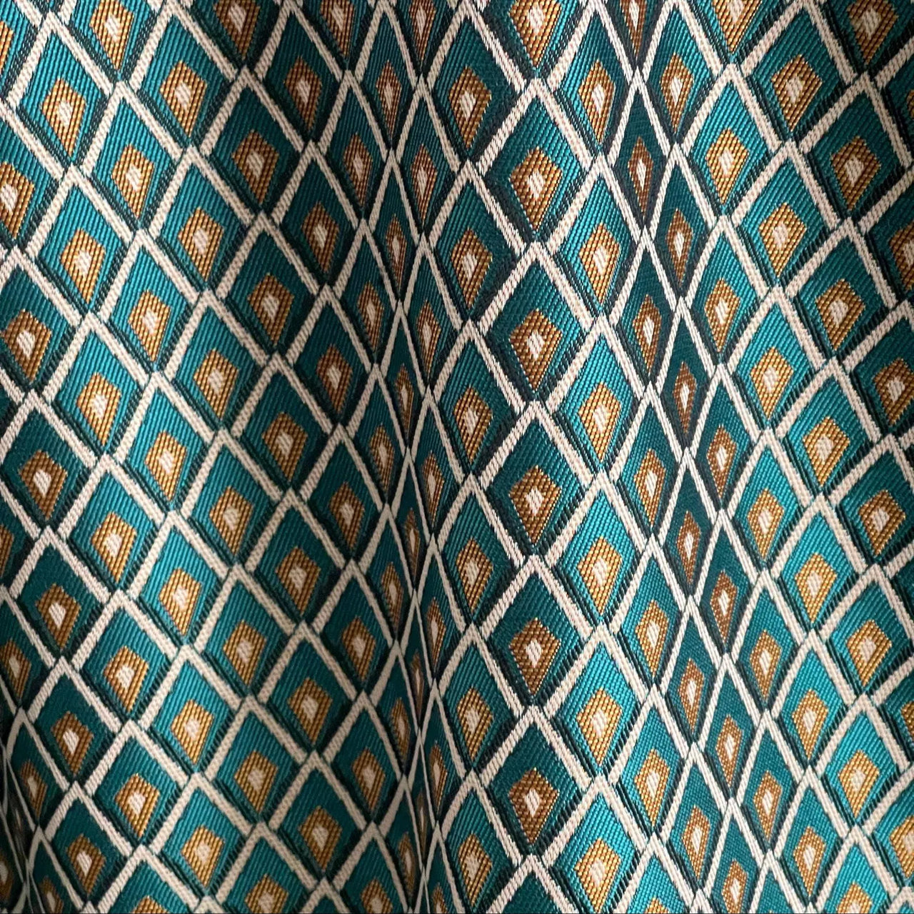 Teal blue geometric fabric showing detailed jacquard weave texture