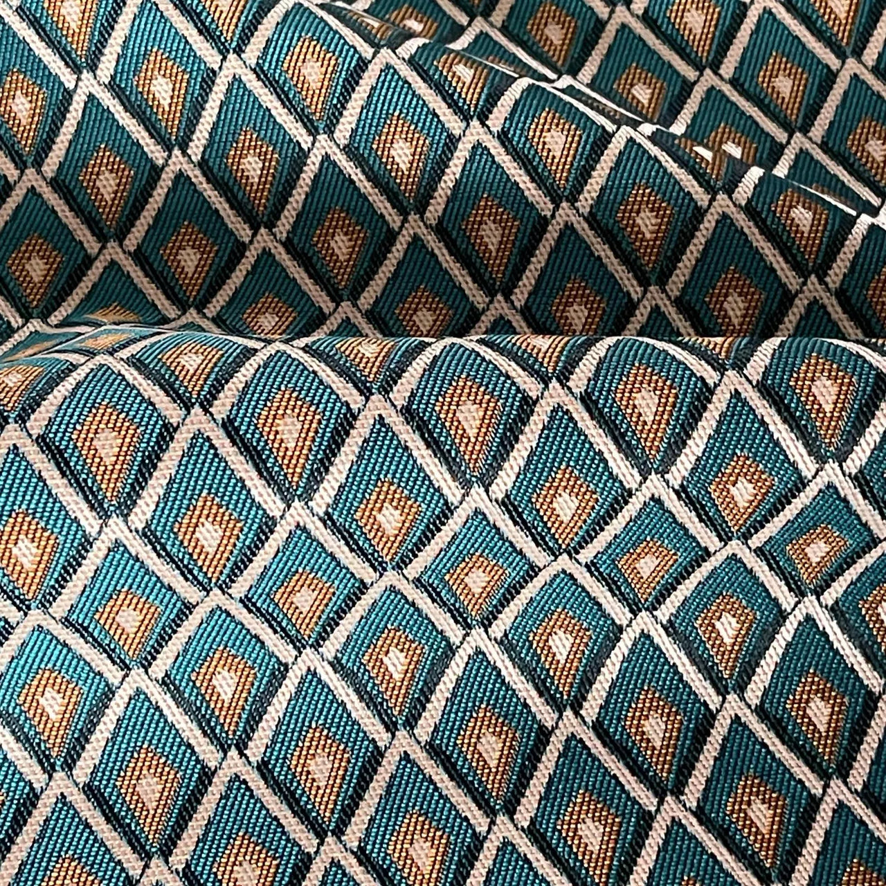 Folded teal and gold lattice fabric highlighting soft drape and structure