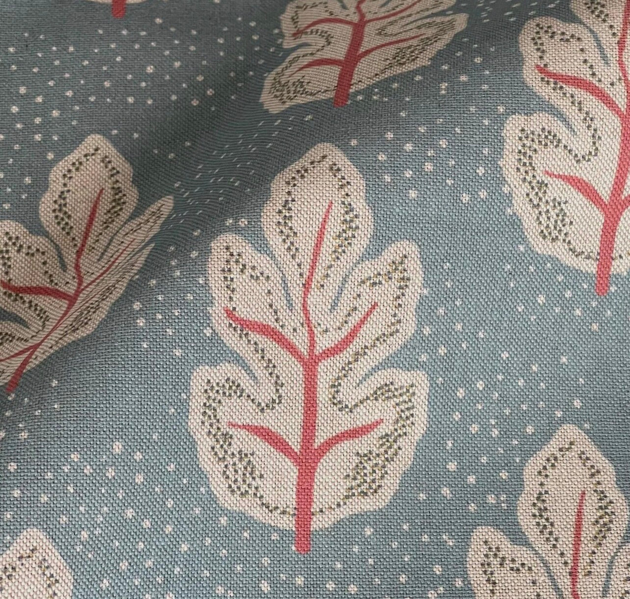 Close-up of cream Nordic leaves with coral stems on textured teal fabric