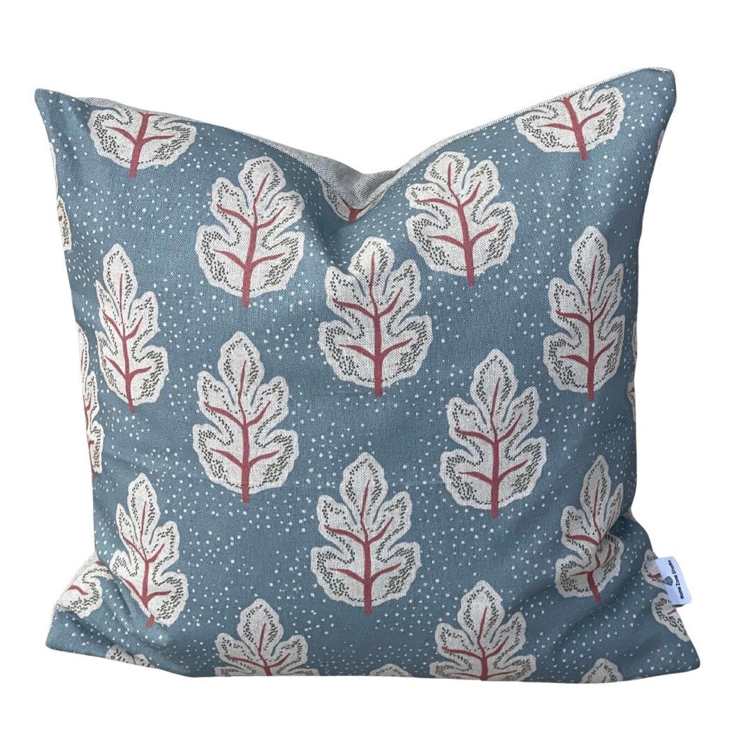 Close-up of cream Nordic leaves with coral stems on teal fabric