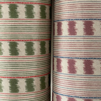 Thumbnail for Two rolls of fabric with geometric patterns, one green and white, the other purple and white.