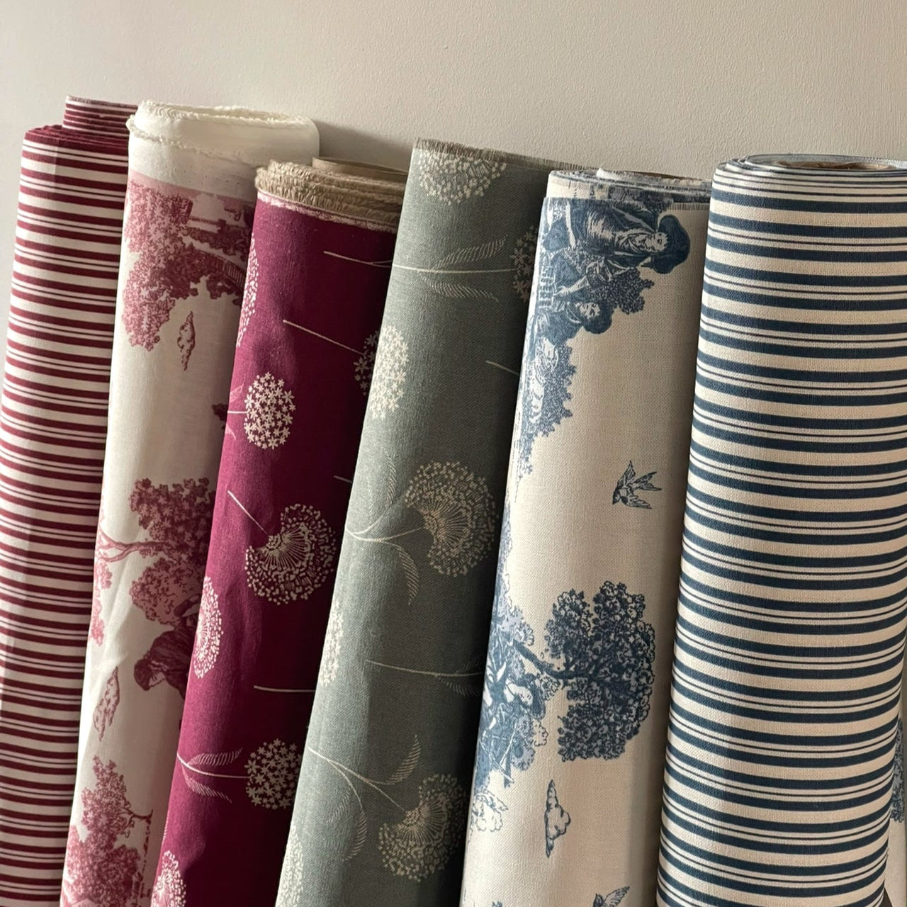 Rolls of fabric with various patterns on a neutral background