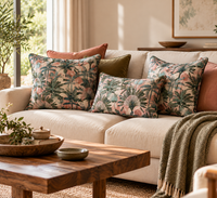 Thumbnail for Three blush pink and green tropical palm cushions arranged on a cream sofa with terracotta and olive green pillows in a stylish botanical living room.