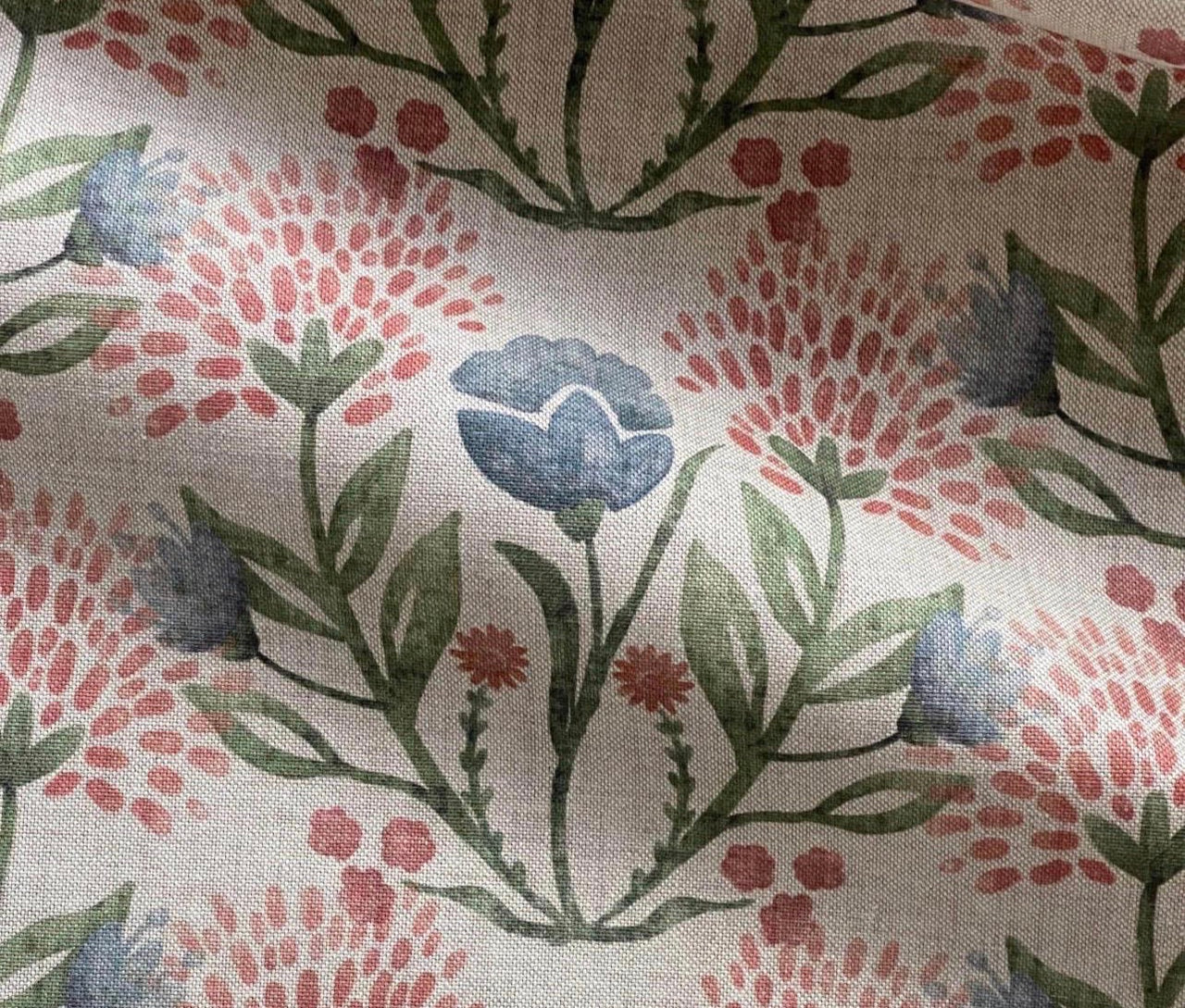 Close-up of blue and blush pink meadow flowers with green leaves on natural fabric